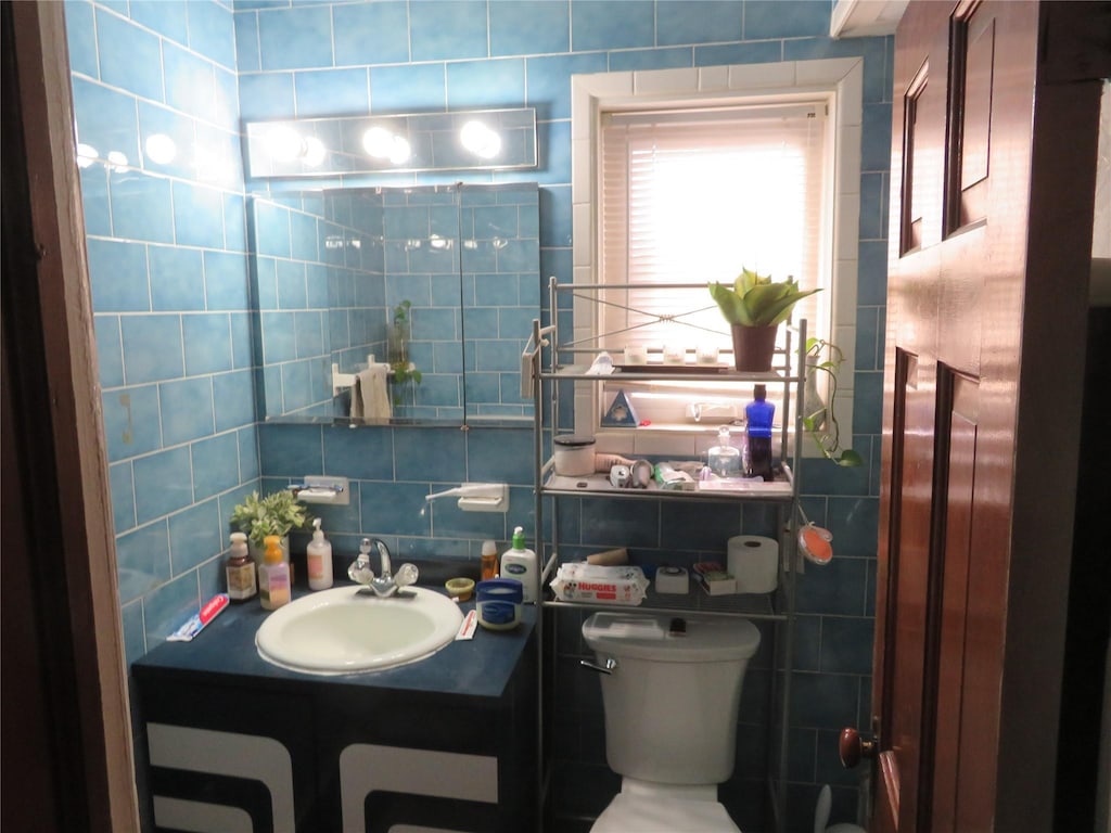 bathroom with decorative backsplash, toilet, tile walls, and vanity