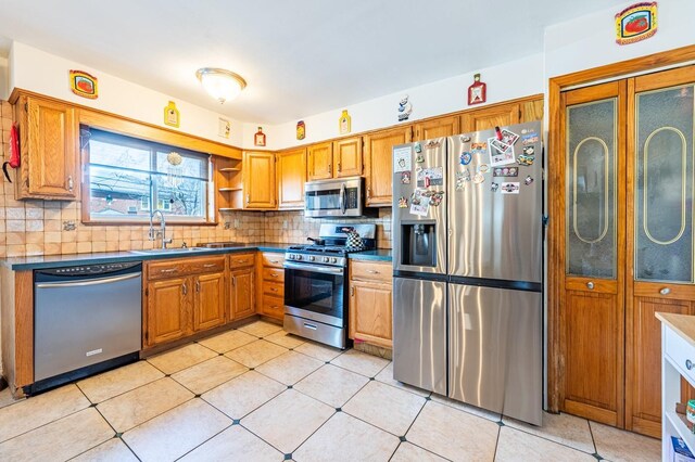 3125 Spencer Dr, Bronx, NY 10465 - kitchen featuring dark countertops, a sink, stainless steel appliances, brown cabinets, and decorative backsplash