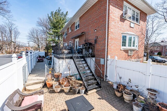 3125 Spencer Dr, Bronx, NY 10465 - view of home's exterior with brick siding, fence, a patio, and stairway