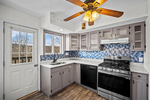 kitchen featuring stainless steel gas range oven, gray cabinetry, under cabinet range hood, dishwasher, and a sink