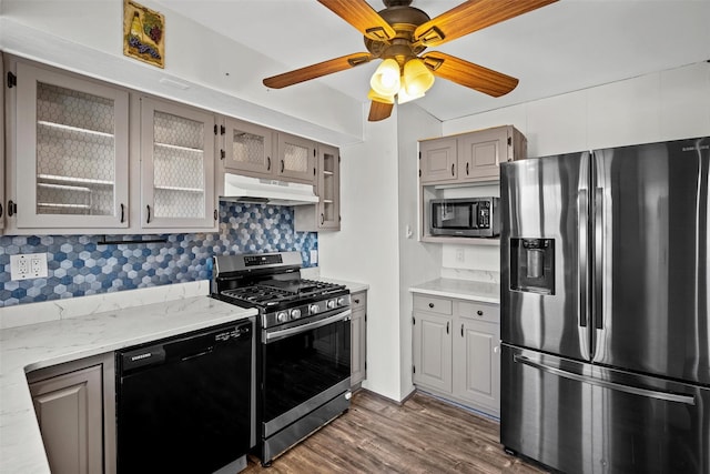 kitchen featuring glass insert cabinets, under cabinet range hood, stainless steel appliances, a ceiling fan, and dark wood-style flooring