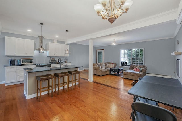 kitchen with wall chimney range hood, dark countertops, stainless steel appliances, light wood finished floors, and a baseboard radiator