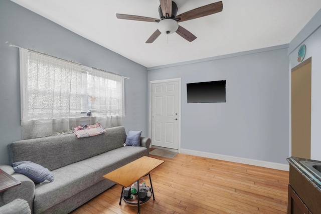 living area featuring baseboards, light wood-type flooring, and ceiling fan