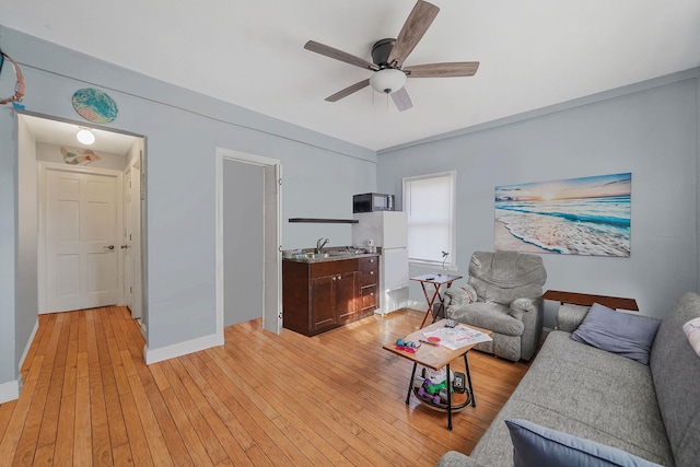 living area with light wood-style flooring, baseboards, and ceiling fan