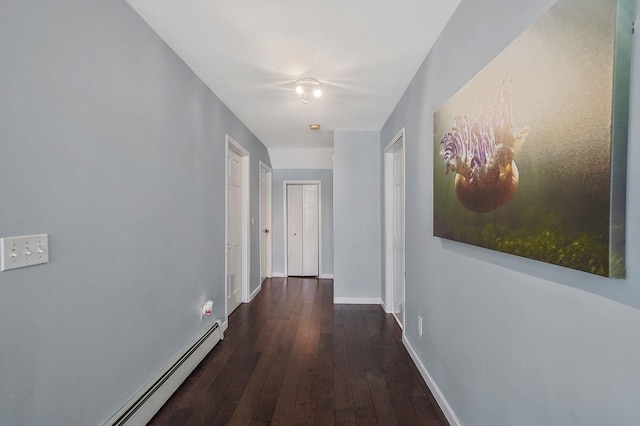 corridor with a baseboard radiator, wood-type flooring, and baseboards