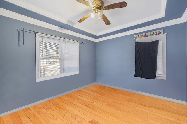 empty room featuring a ceiling fan, crown molding, baseboards, and wood finished floors