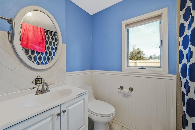 full bathroom with vanity, toilet, a wainscoted wall, and tile patterned flooring