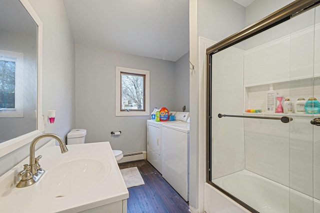 bathroom with vanity, wood finished floors, a baseboard heating unit, toilet, and washing machine and dryer