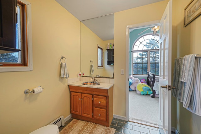 bathroom featuring toilet, vanity, baseboards, and a baseboard radiator