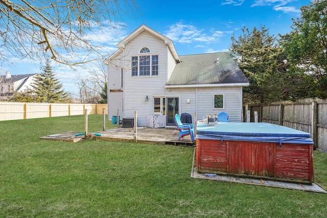 back of house featuring a lawn, a hot tub, and a fenced backyard