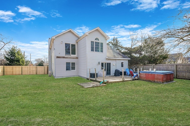 back of house with a yard, a fenced backyard, and a hot tub