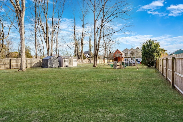 view of yard featuring a fenced backyard, a storage shed, an outdoor structure, and a playground