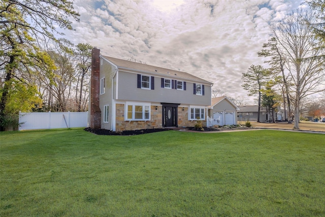 colonial home featuring a front lawn, fence, a chimney, a garage, and stone siding