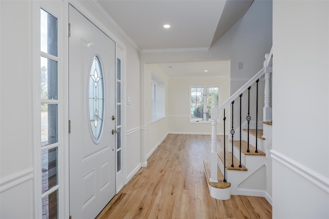 entrance foyer with crown molding, stairway, baseboards, and light wood finished floors