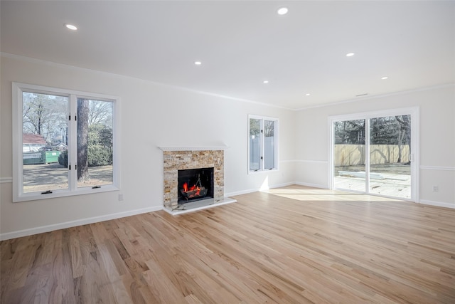 unfurnished living room with a fireplace, light wood-style flooring, a healthy amount of sunlight, and ornamental molding