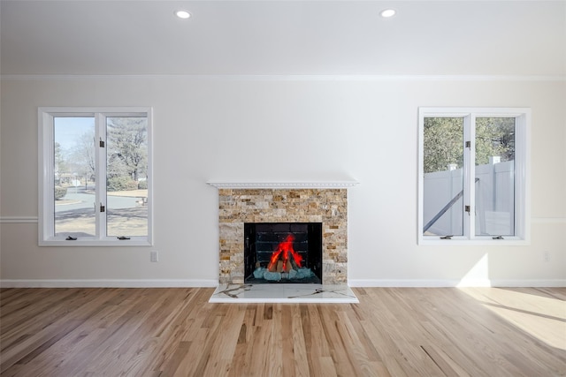 unfurnished living room with crown molding, plenty of natural light, wood finished floors, and baseboards