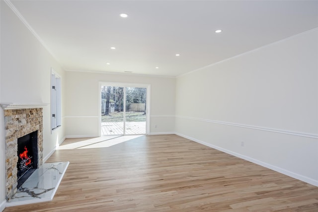 unfurnished living room featuring a premium fireplace, light wood-style flooring, baseboards, and ornamental molding