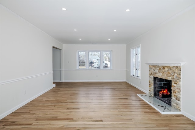 unfurnished living room featuring recessed lighting, baseboards, light wood-style floors, and a premium fireplace