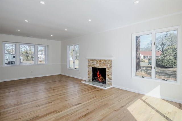 unfurnished living room with recessed lighting, baseboards, light wood-style flooring, and a fireplace