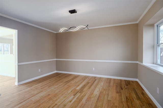 spare room with baseboards, plenty of natural light, crown molding, and light wood finished floors