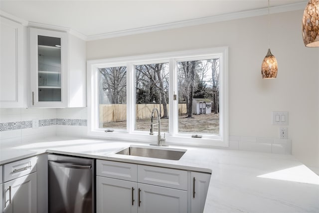 kitchen featuring pendant lighting, ornamental molding, a sink, white cabinetry, and glass insert cabinets