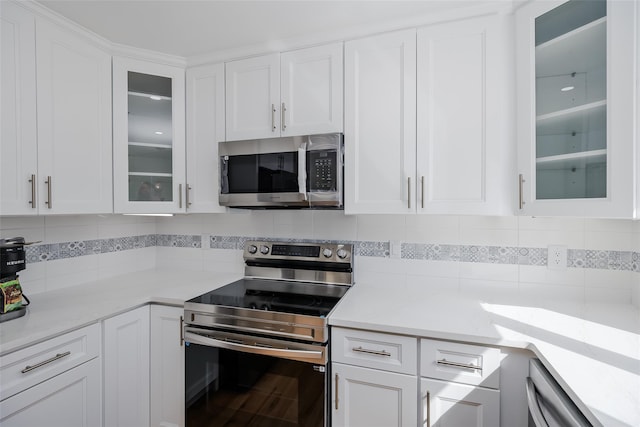 kitchen featuring decorative backsplash, white cabinets, stainless steel appliances, and light countertops