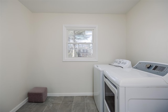 clothes washing area featuring laundry area, baseboards, tile patterned floors, and washing machine and clothes dryer