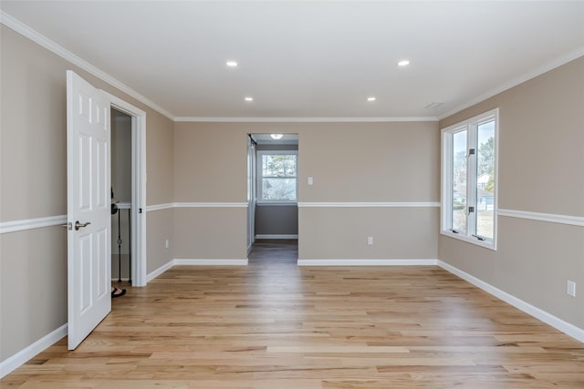 empty room with light wood-type flooring, crown molding, and baseboards