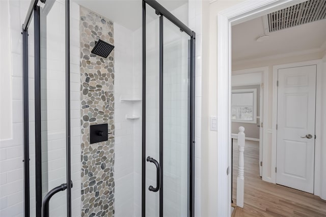 bathroom with a shower stall, crown molding, wood finished floors, and visible vents