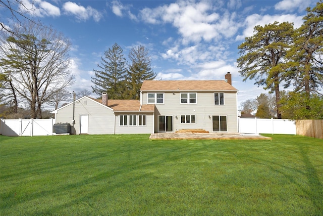 back of house featuring a lawn, a chimney, a fenced backyard, a patio area, and a gate