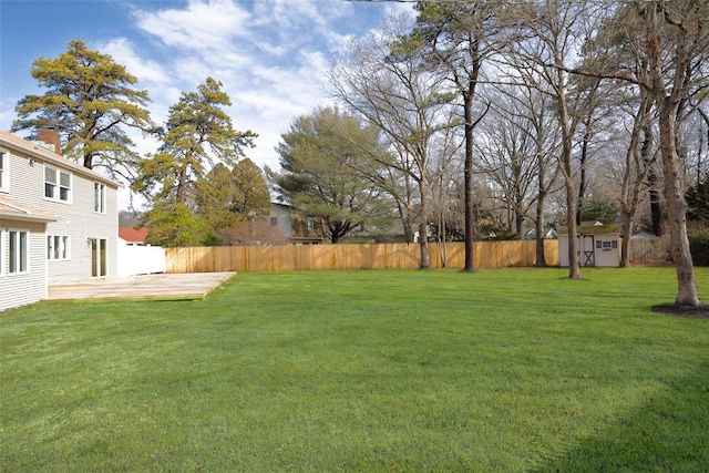 view of yard featuring a deck, an outdoor structure, and fence