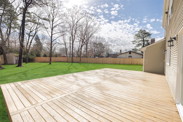 wooden terrace with a storage unit, an outdoor structure, a fenced backyard, and a lawn