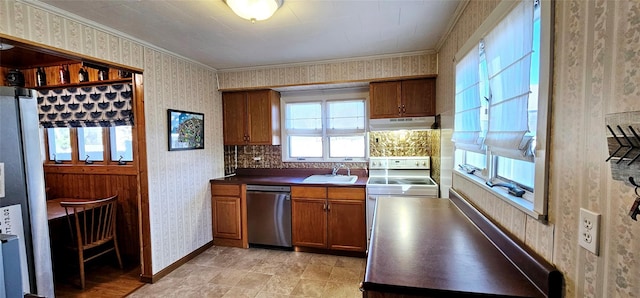 kitchen featuring wallpapered walls, under cabinet range hood, brown cabinets, appliances with stainless steel finishes, and a sink