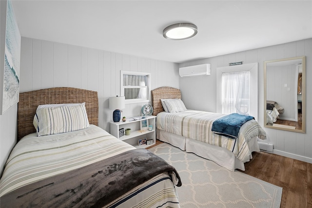 bedroom featuring a baseboard heating unit, an AC wall unit, and wood finished floors