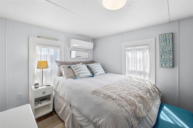 bedroom with wood finished floors, a wall mounted air conditioner, and a textured ceiling