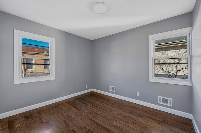 empty room with visible vents, baseboards, and dark wood-style flooring