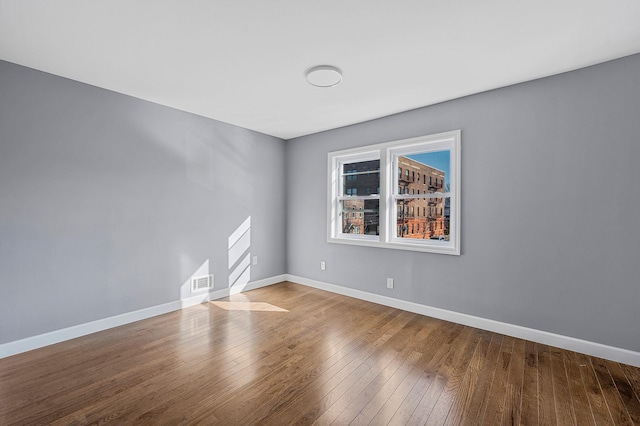 unfurnished room featuring visible vents, baseboards, and hardwood / wood-style floors