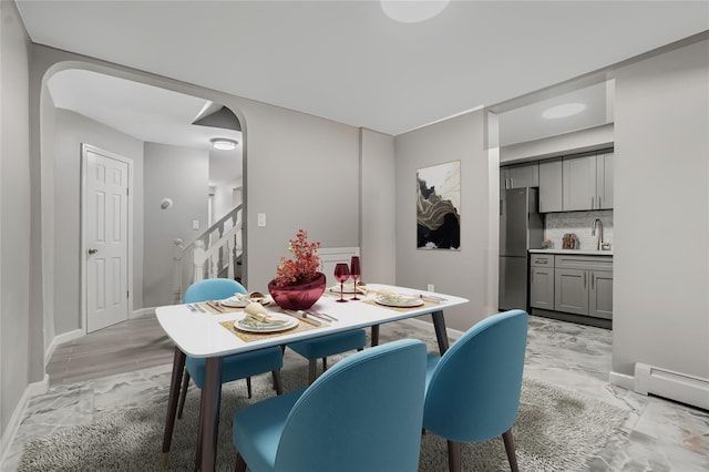 dining room with marble finish floor, a baseboard heating unit, stairway, arched walkways, and baseboards