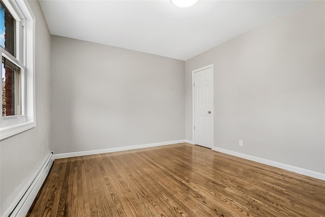 spare room with a baseboard radiator, baseboards, and wood finished floors