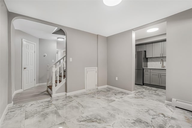 unfurnished living room with stairway, baseboards, marble finish floor, and a baseboard radiator