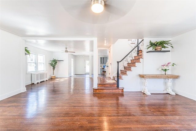 foyer entrance featuring baseboards, stairs, radiator heating unit, wood finished floors, and a ceiling fan