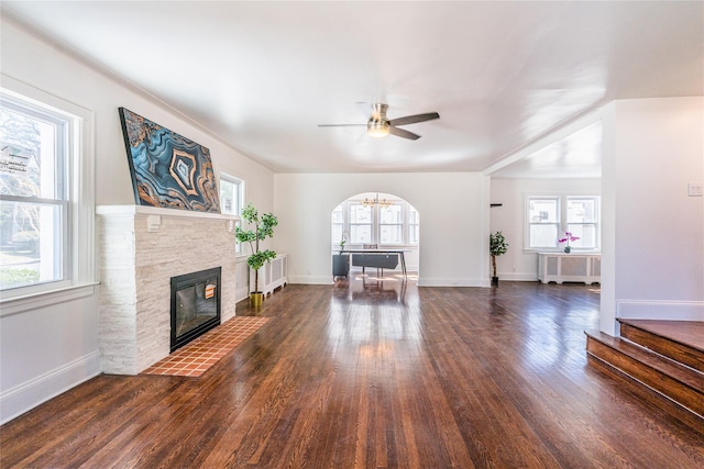 unfurnished living room with radiator heating unit, wood finished floors, plenty of natural light, and ceiling fan