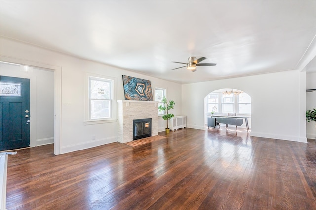 unfurnished living room with radiator, a ceiling fan, baseboards, a fireplace with flush hearth, and wood-type flooring