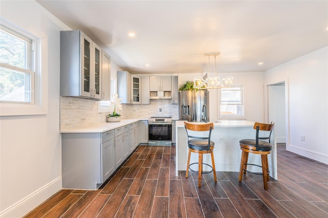 kitchen featuring backsplash, extractor fan, wood tiled floor, gray cabinets, and appliances with stainless steel finishes