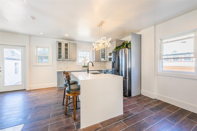 kitchen with backsplash, light countertops, an inviting chandelier, and wood tiled floor