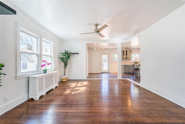 interior space featuring baseboards, radiator, wood finished floors, and a ceiling fan