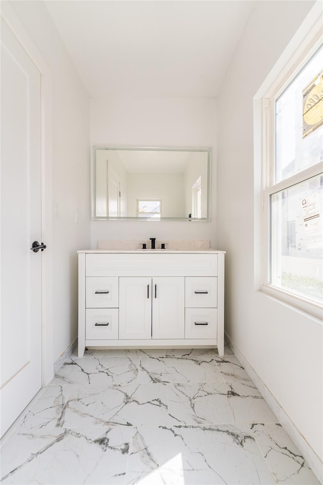 bathroom with vanity, baseboards, and marble finish floor