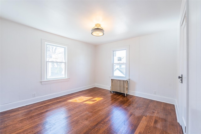 spare room featuring hardwood / wood-style floors, radiator heating unit, and baseboards