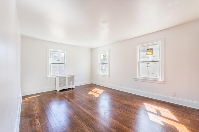 unfurnished room with radiator heating unit, wood finished floors, and baseboards