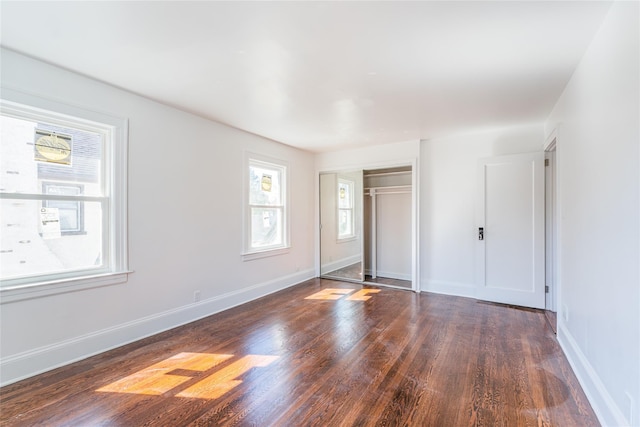 unfurnished bedroom featuring wood finished floors, baseboards, and a closet